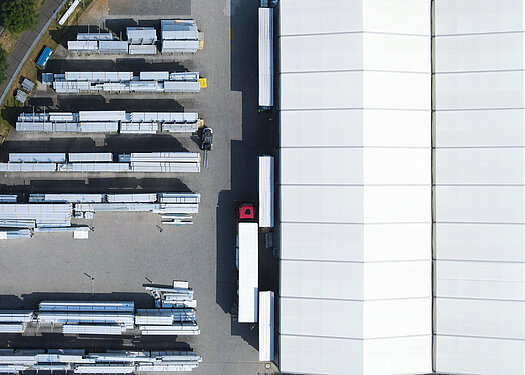 [Translate to English:] Auf dem Gelände von Herchenbach wird das Material für Leichtbauhallen verladen.